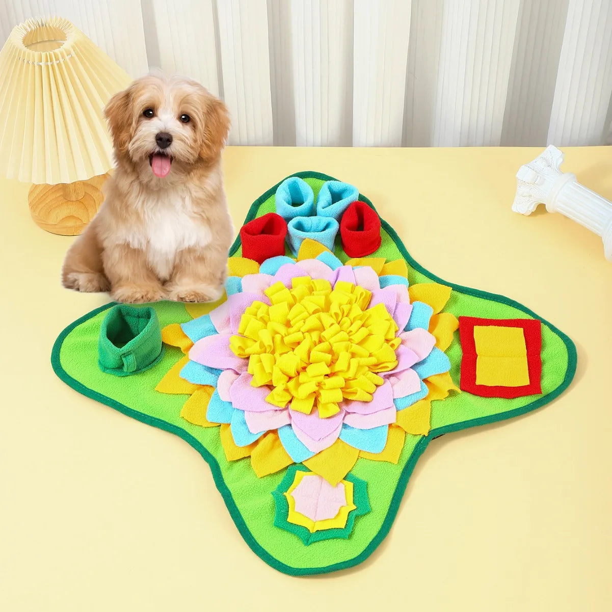 Dog sitting next to a colorful flower-shaped mat on a yellow surface.