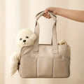 Beige tote bag held by a hand with a white teddy bear and rolled-up mat inside, on a light beige background.